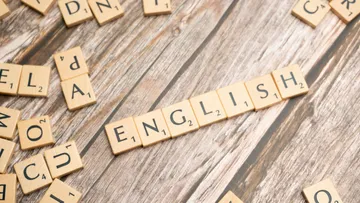 Scrabble tiles spelling 'ENGLISH' on wooden table.