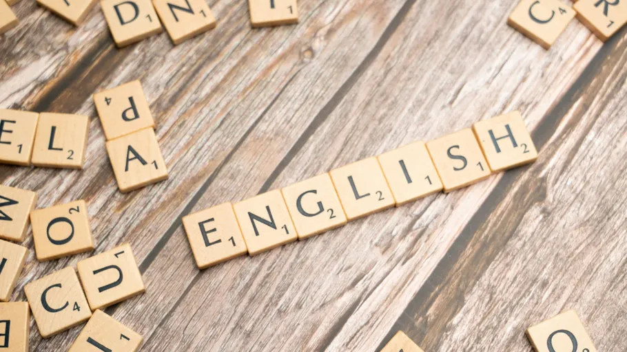 Scrabble tiles spelling 'ENGLISH' on wooden table.
