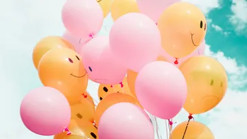 Smiley balloons floating in clear sky.