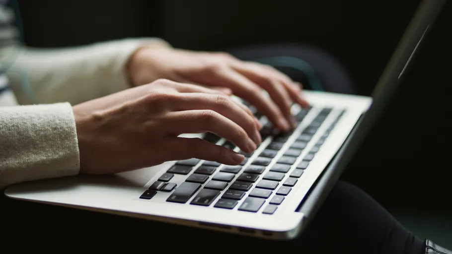 Person tippt auf Laptop im gedämpften Licht.