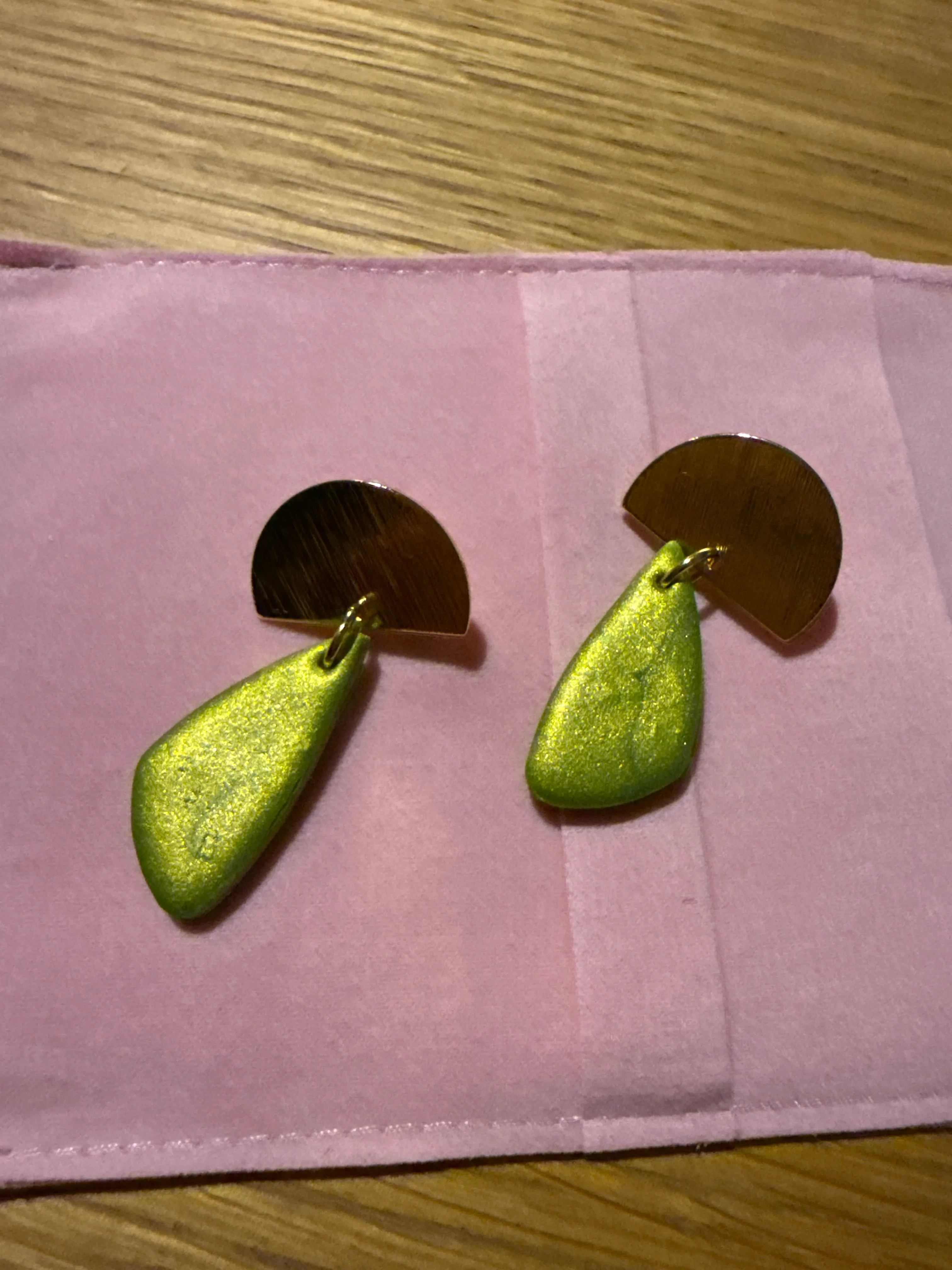 Earrings on pink fabric, wooden table.