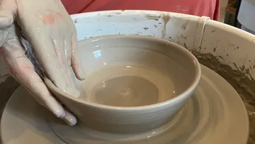 Potter shaping bowl on a potter's wheel.