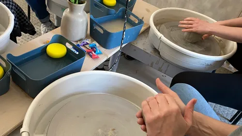 Hände formen Ton auf Töpferscheibe drinnen.
