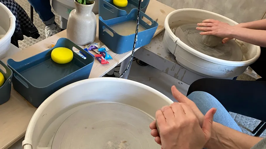 Hände formen Ton auf Töpferscheibe drinnen.