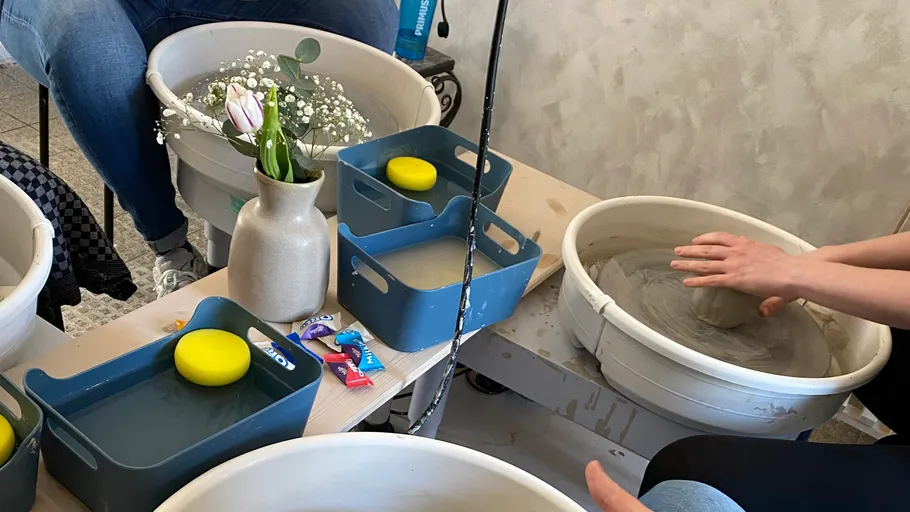 Hände formen Ton auf Töpferscheibe drinnen.