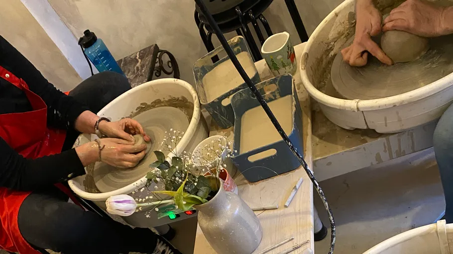 Zwei Personen benutzen Töpferscheiben drinnen.