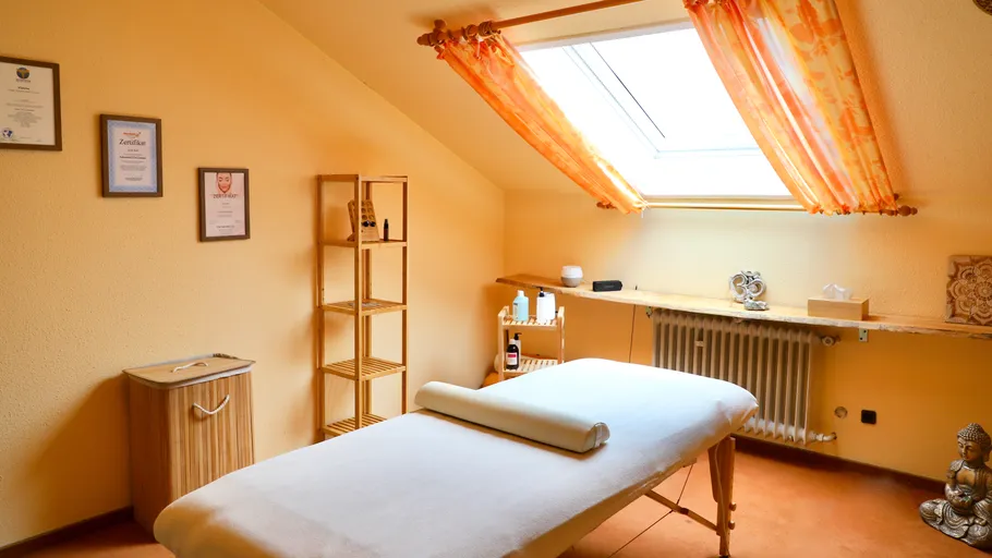 Massagetisch in gemütlichem, sonnigem Raum.