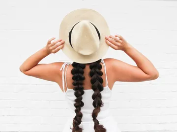 Woman with pigtails puts on a straw hat.