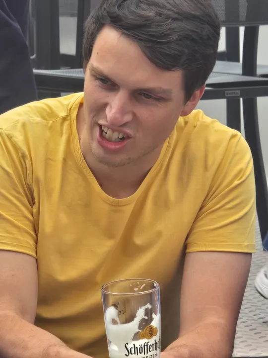 Man in yellow shirt making a face indoors.