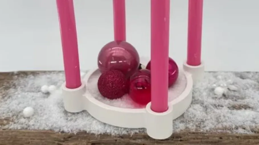 Rosa Kerzenhalter mit roten Kugeln im Schnee.