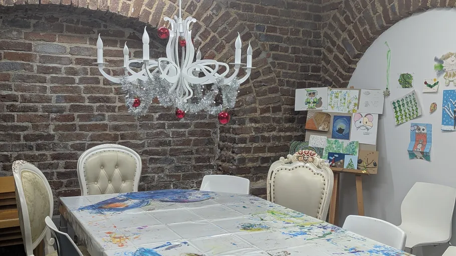 Art table with chandelier in brick room.