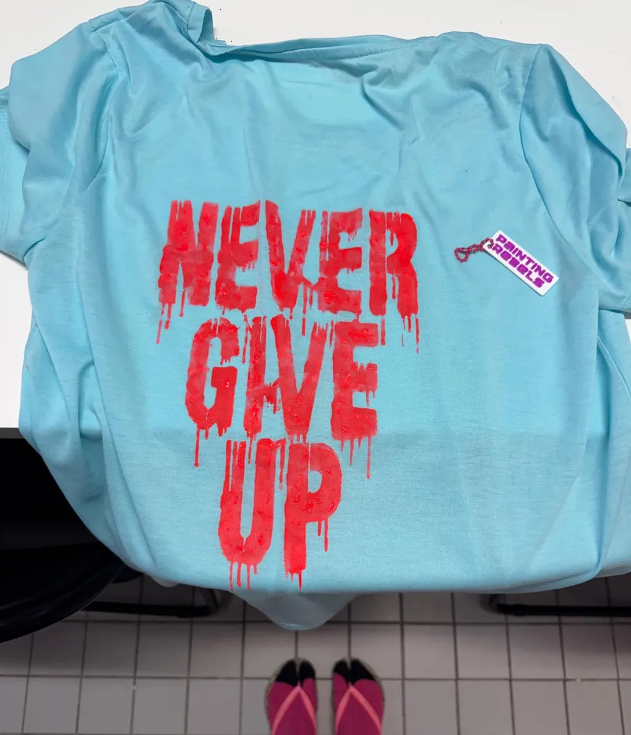 Blaues Shirt mit rotem Text 'Never Give Up'.