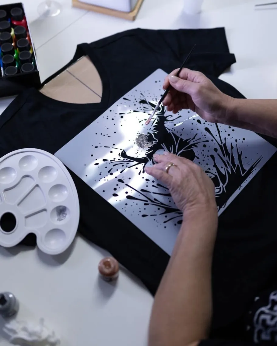 Person painting design on black T-shirt.