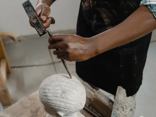 Ein Künstler schnitzt eine Skulptur in einem Atelier.