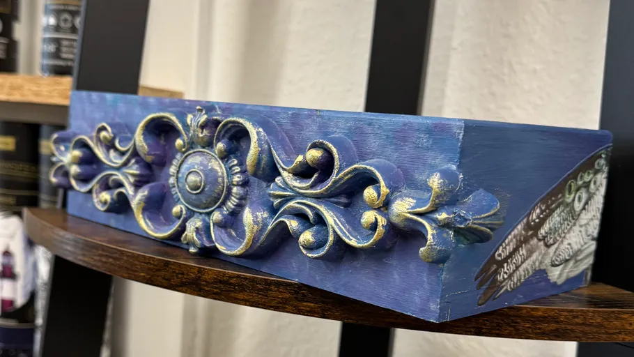 Ornamentales Holzstück mit blauen und goldenen Akzenten.