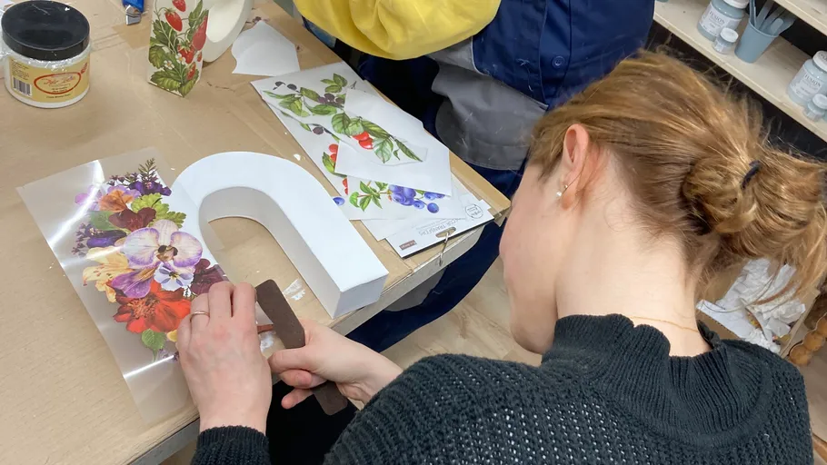 Person dekoriert Buchstaben mit Blumendesigns.