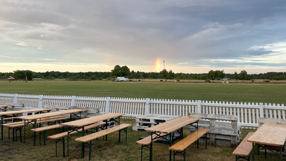Empty benches overlook a field with a rainbow.