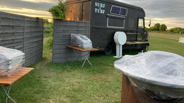 Food truck in field with wrapped tables.