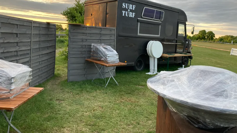 Foodtruck im Feld mit eingepackten Tischen.