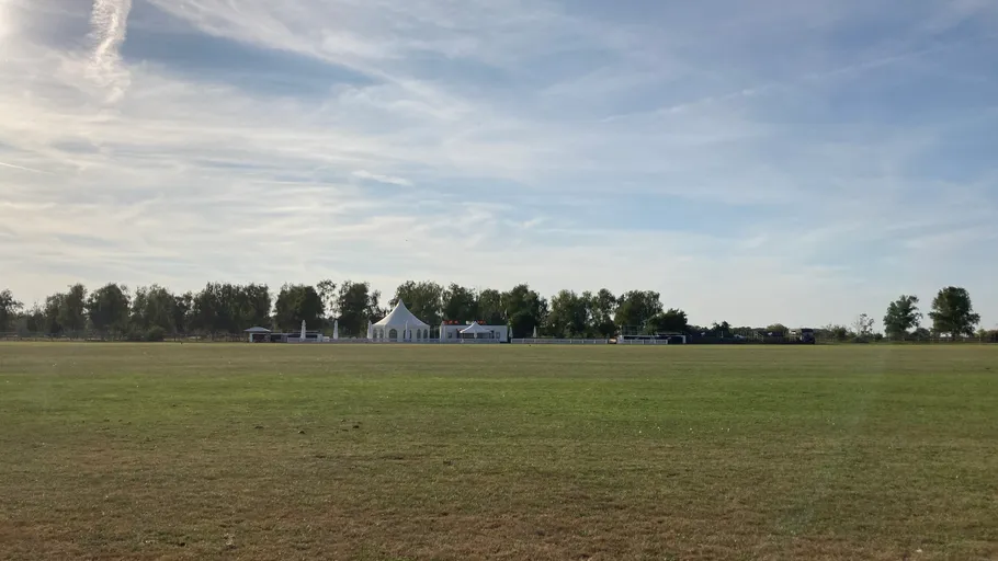 Weißes Zelt auf Grasfeld unter blauem Himmel.