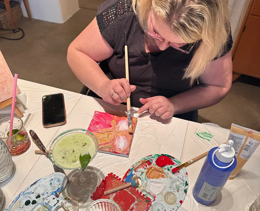 Woman painting on canvas at a table.