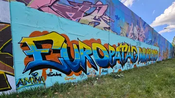 Colorful graffiti on a large wall outdoors.