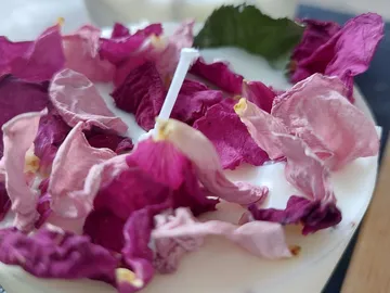 Kerze mit getrockneten Rosenblättern und Docht in Wachs.