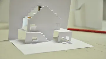 Papiermodellhaus auf flacher Oberfläche, künstlerische Kreation.