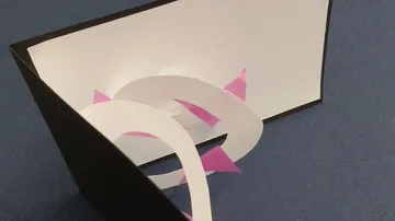 Papierskulptur mit Spiralen auf blauem Hintergrund.