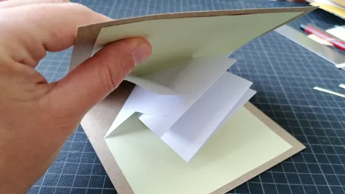 Hand öffnet Pop-up-Karte auf Tisch.