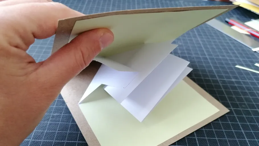 Hand öffnet Pop-up-Karte auf Tisch.