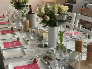 Elegant gedeckter Tisch mit Blumen, Gläsern und Geschirr.