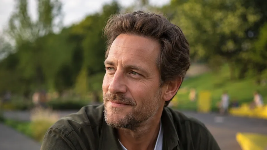 Man smiling outdoors in green park.