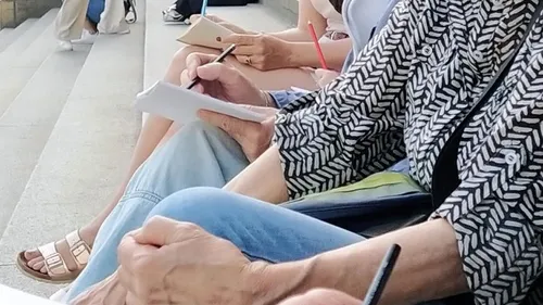 People writing on notepads, sitting on steps.