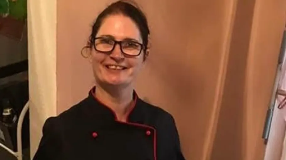 Person in chef uniform smiling indoors.