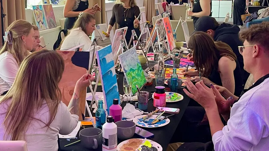 People painting canvases in a workshop setting.
