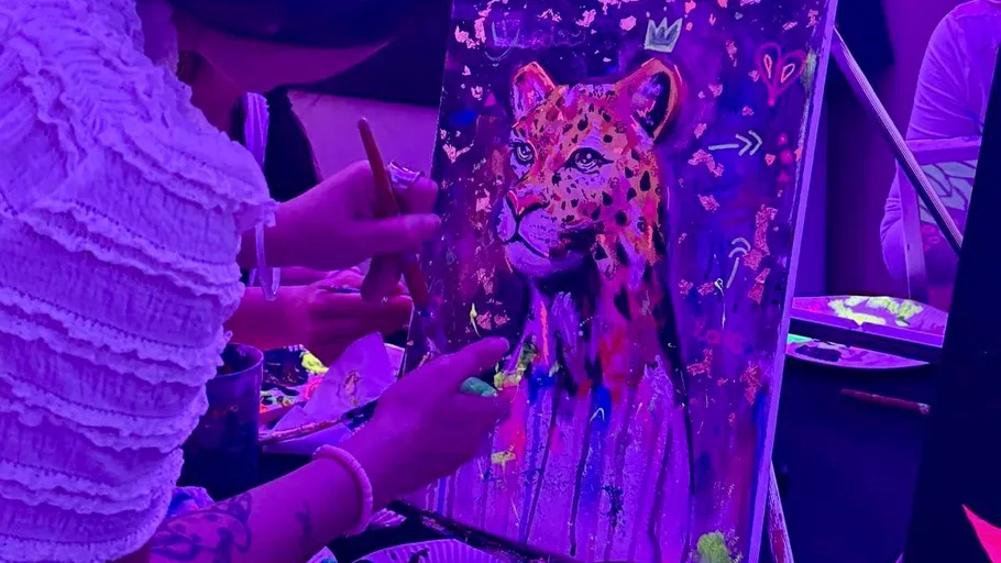 Person painting leopard under purple lights.