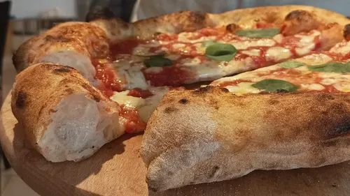 Pizza Margherita auf Holzbrett, geschnitten.