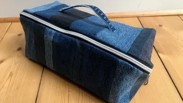 Patchwork denim bag with handle on wooden floor.