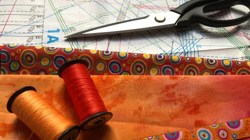 Scissors with fabric, thread, and pattern paper.