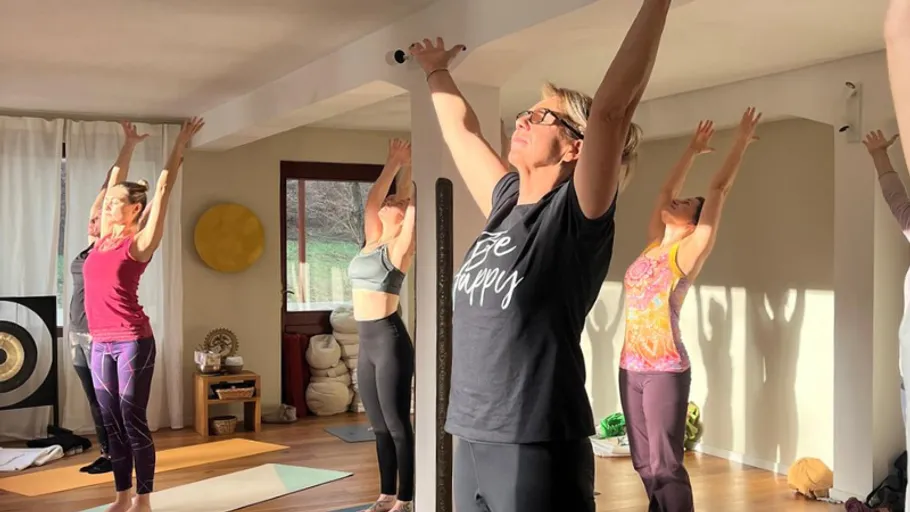 Group doing yoga stretches in sunlit room.