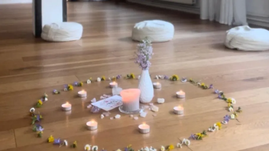 Candles and flowers arranged on wooden floor.