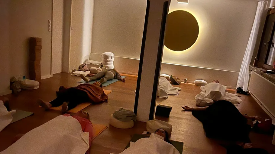 People lying on mats in a dark room.
