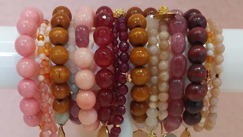 Various beaded bracelets on white stand.