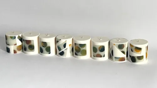 Eight cylindrical candles with geometric designs.