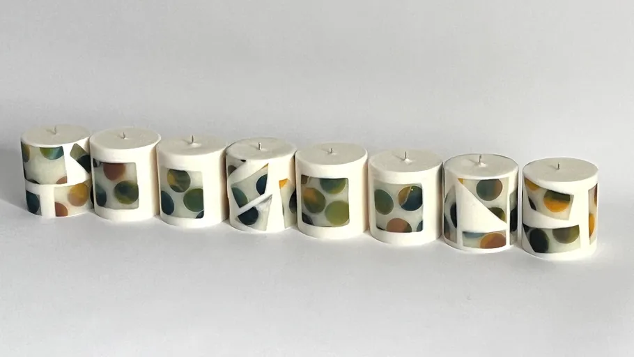 Eight cylindrical candles with geometric designs.