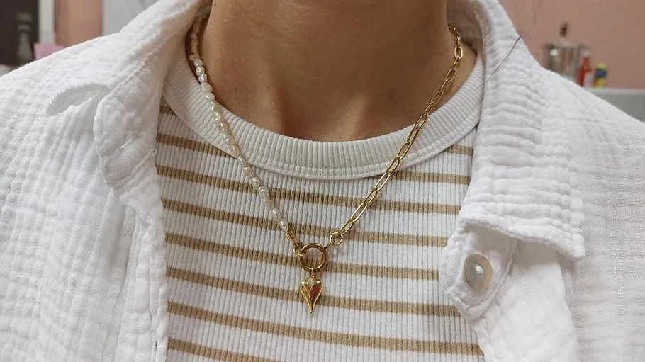 Person wearing layered necklaces and striped shirt.