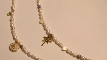 Perlenkette mit Anhängern auf weißer Oberfläche.