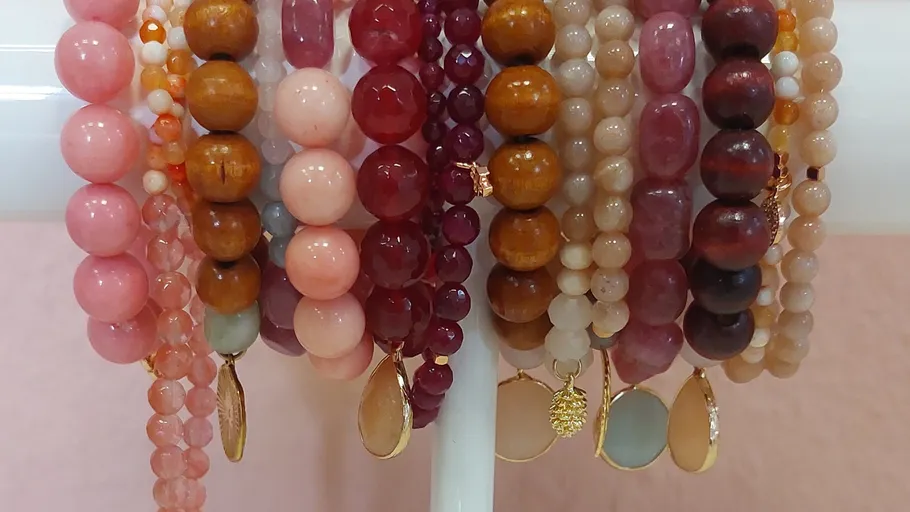Colorful bead bracelets on a white rod.