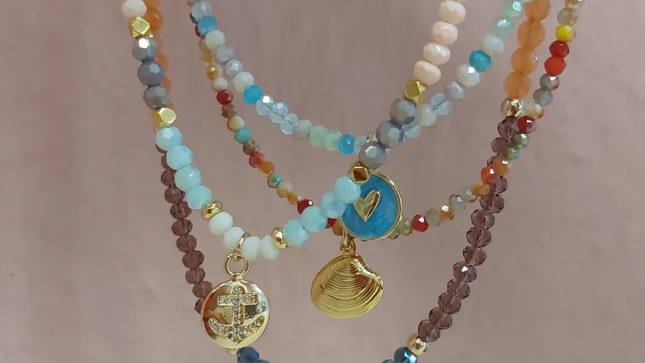 Colorful beaded necklaces with gold charms displayed.